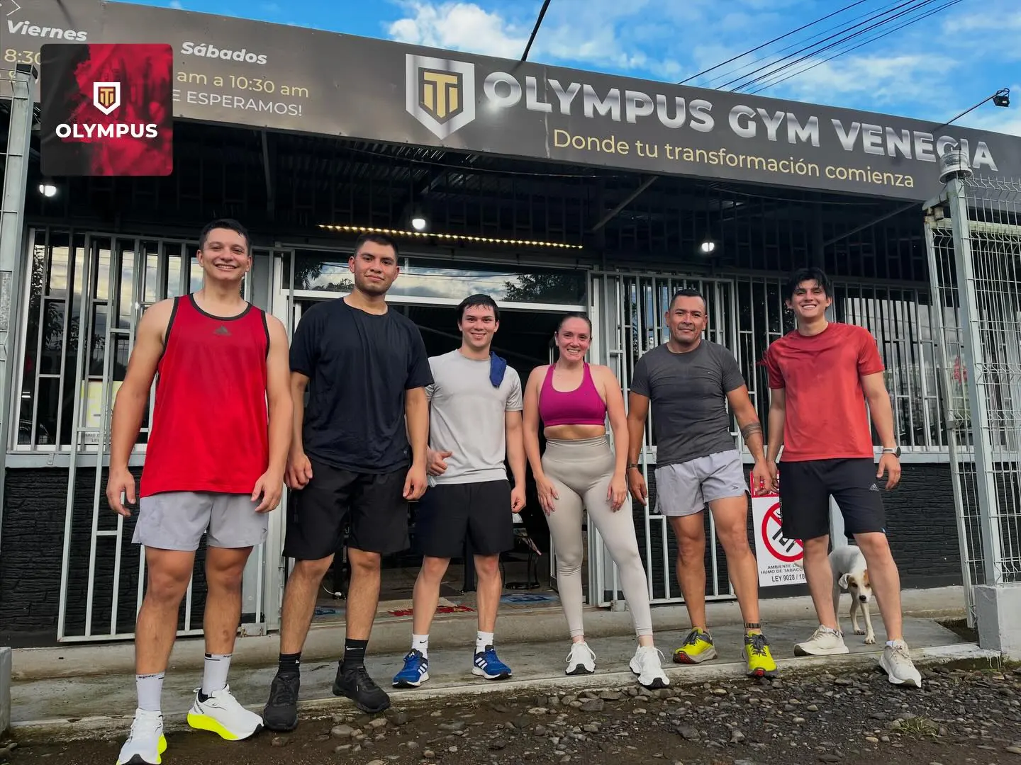 Seis socios de Olympus posan frente a la fachada del gimnasio, bajo el rótulo «Olympus Gym Venecia, donde tu transformación comienza».