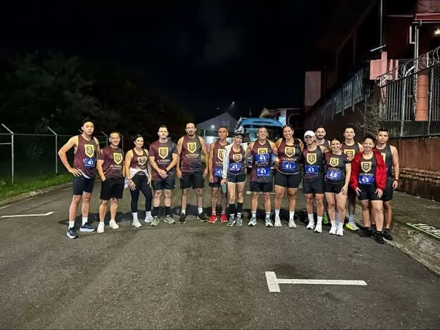 El equipo Olympus, con camisetas iguales, posa de noche en una calle antes de un relevo.