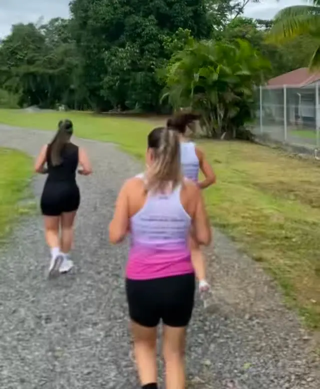 Un grupo de corredoras avanza por un camino de lastre entre potreros y árboles.